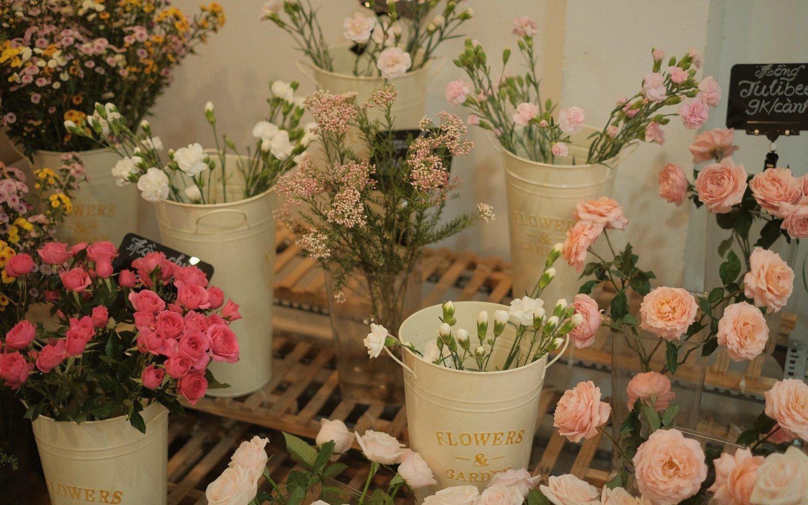 Buckets of roses, carnations and baby's breath displayed at a flower shop