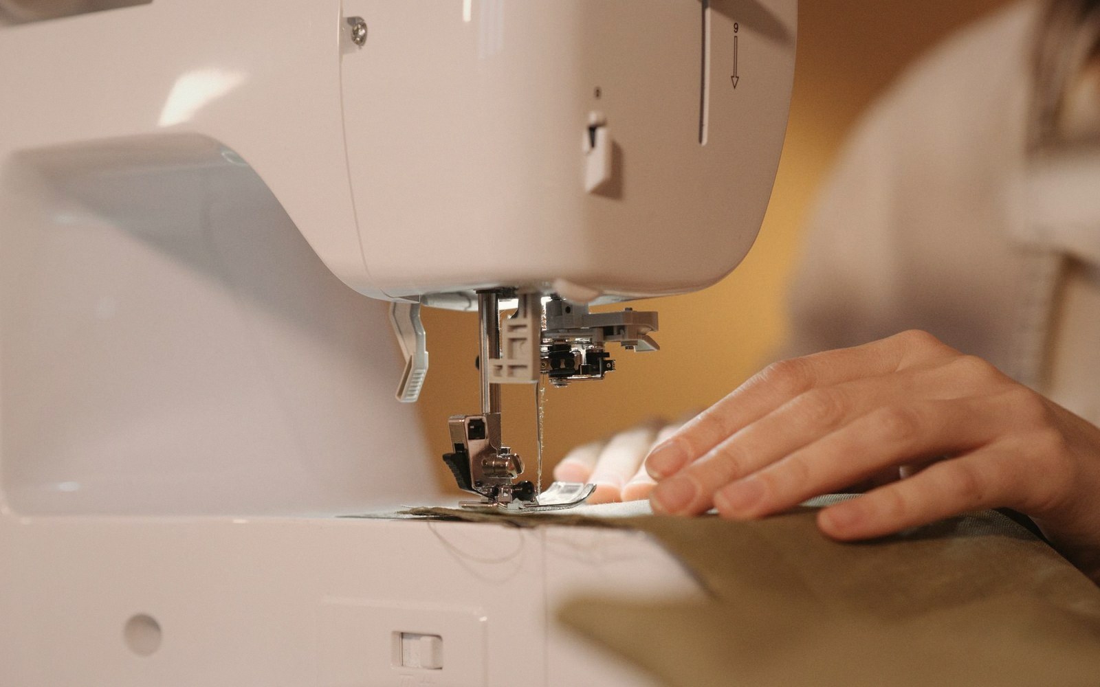 Hands guiding fabric under the needle of a sewing machine
