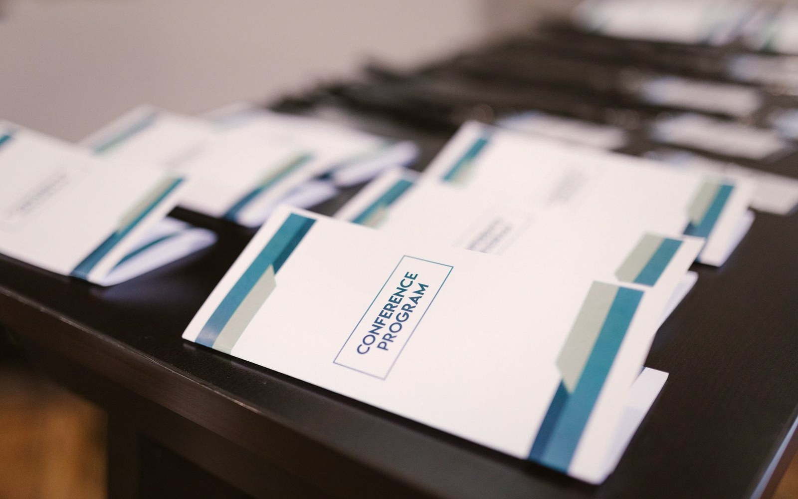 Conference program booklets lined up in rows on a dark table