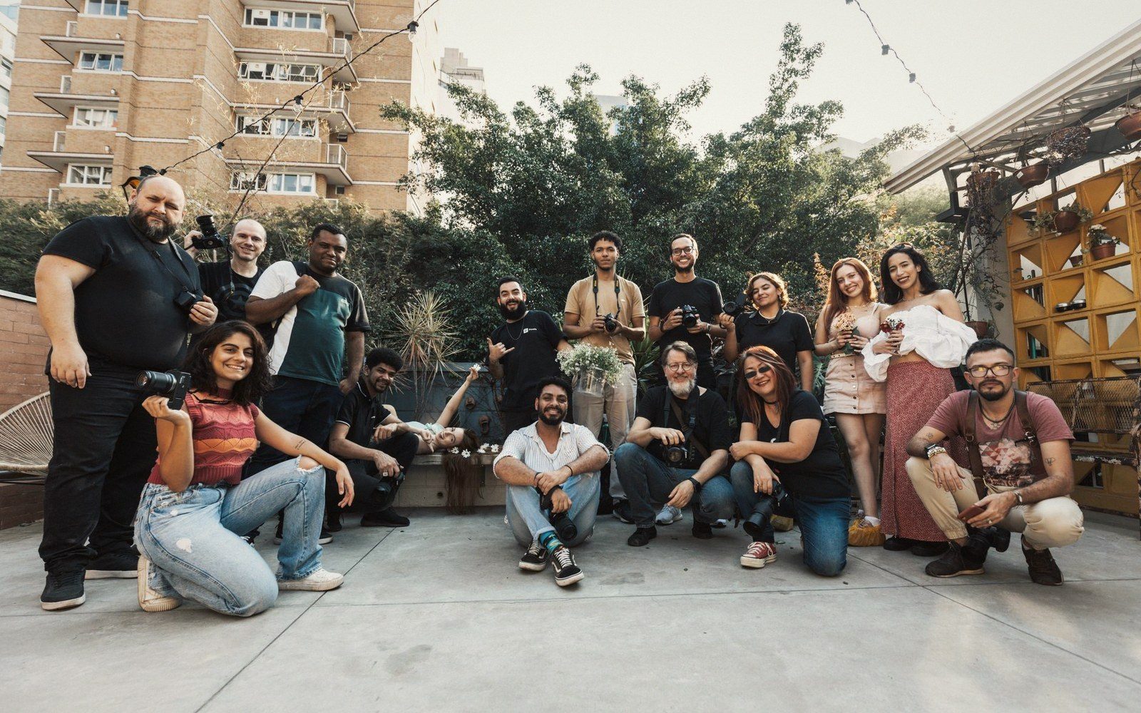 Group of photographers and guests pose together on a rooftop terrace with string lights