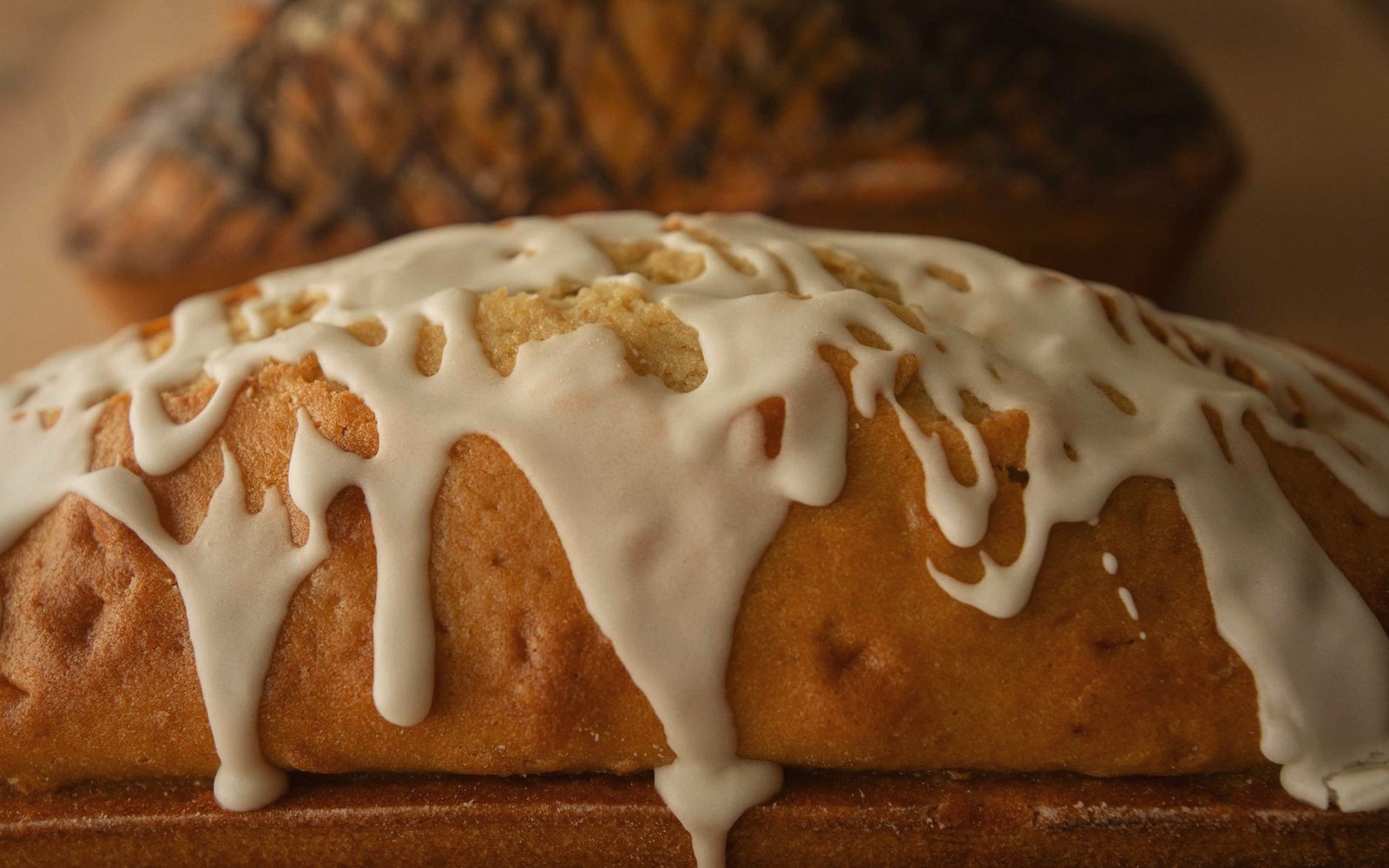 White glaze dripping down the rounded top of a loaf cake