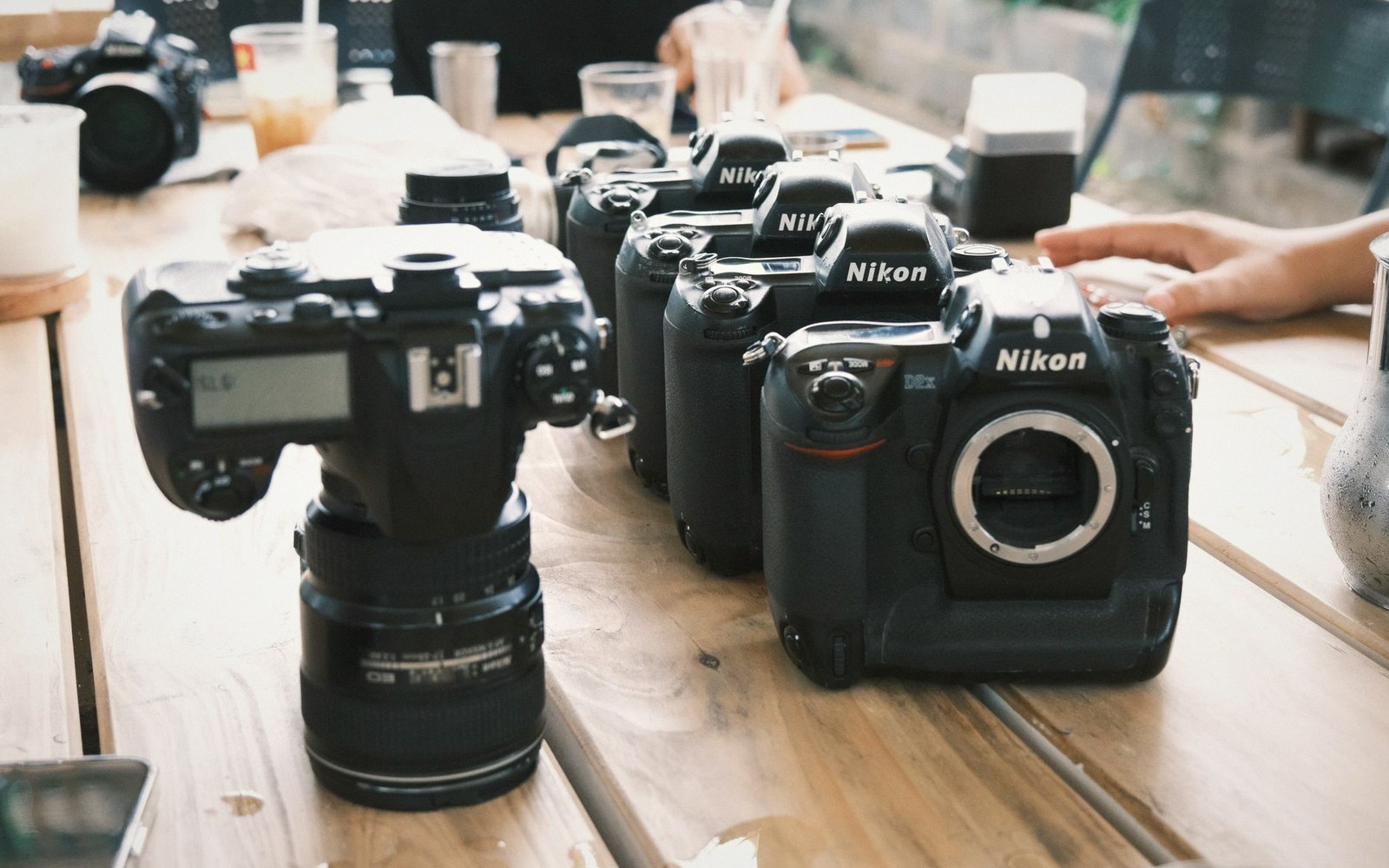 Several Nikon DSLR camera bodies lined up on a wooden table