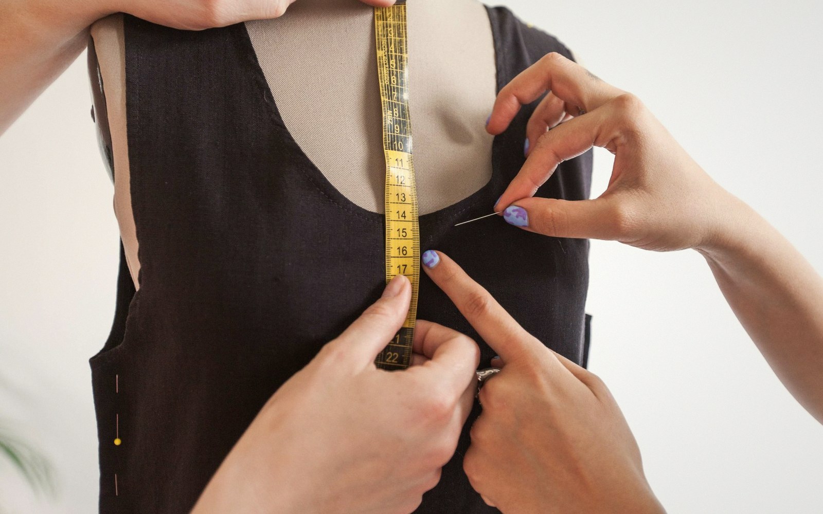 A dressmaker pinning a hem on a stand