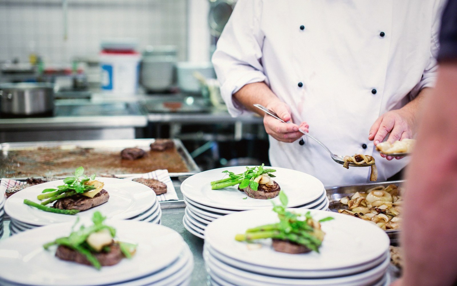 Two cooks plating at speed in a service kitchen